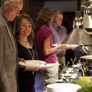 Happy Couples standing in buffet line with empty plates